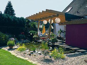 Teichbau Schritt 12: Der fertige Folienteich mit Pflanzen und feinen Kieselsteinen umrandet liegt direkt neben der Terrasse mit einer gemütlichen Hängematte.