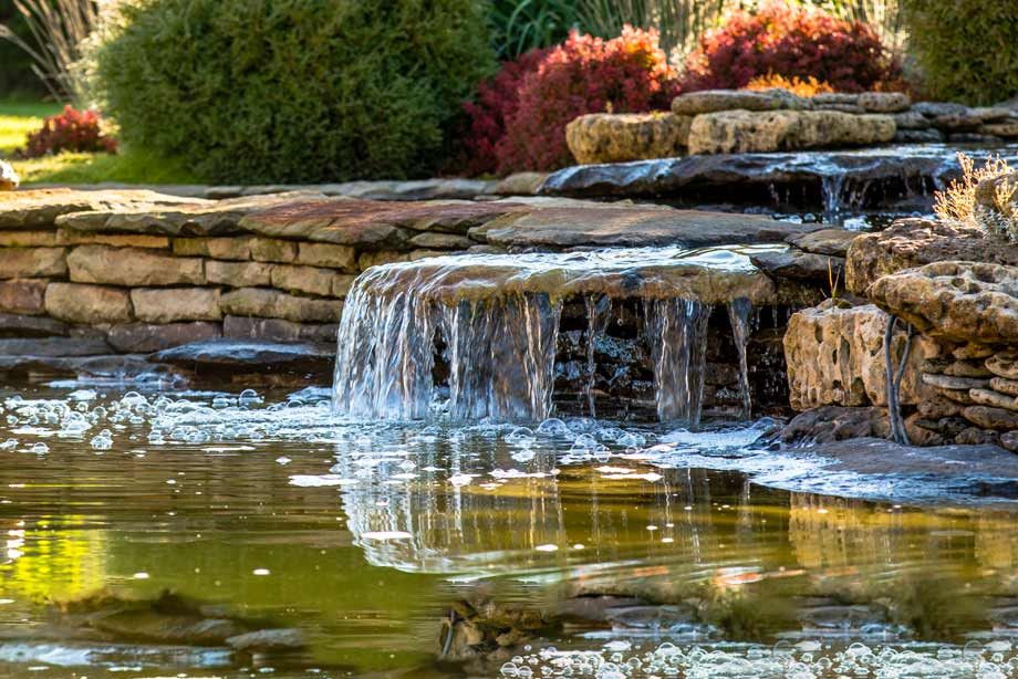 Bachlauf mündet in einem kleinen Wasserfall in den Gartenteich. 